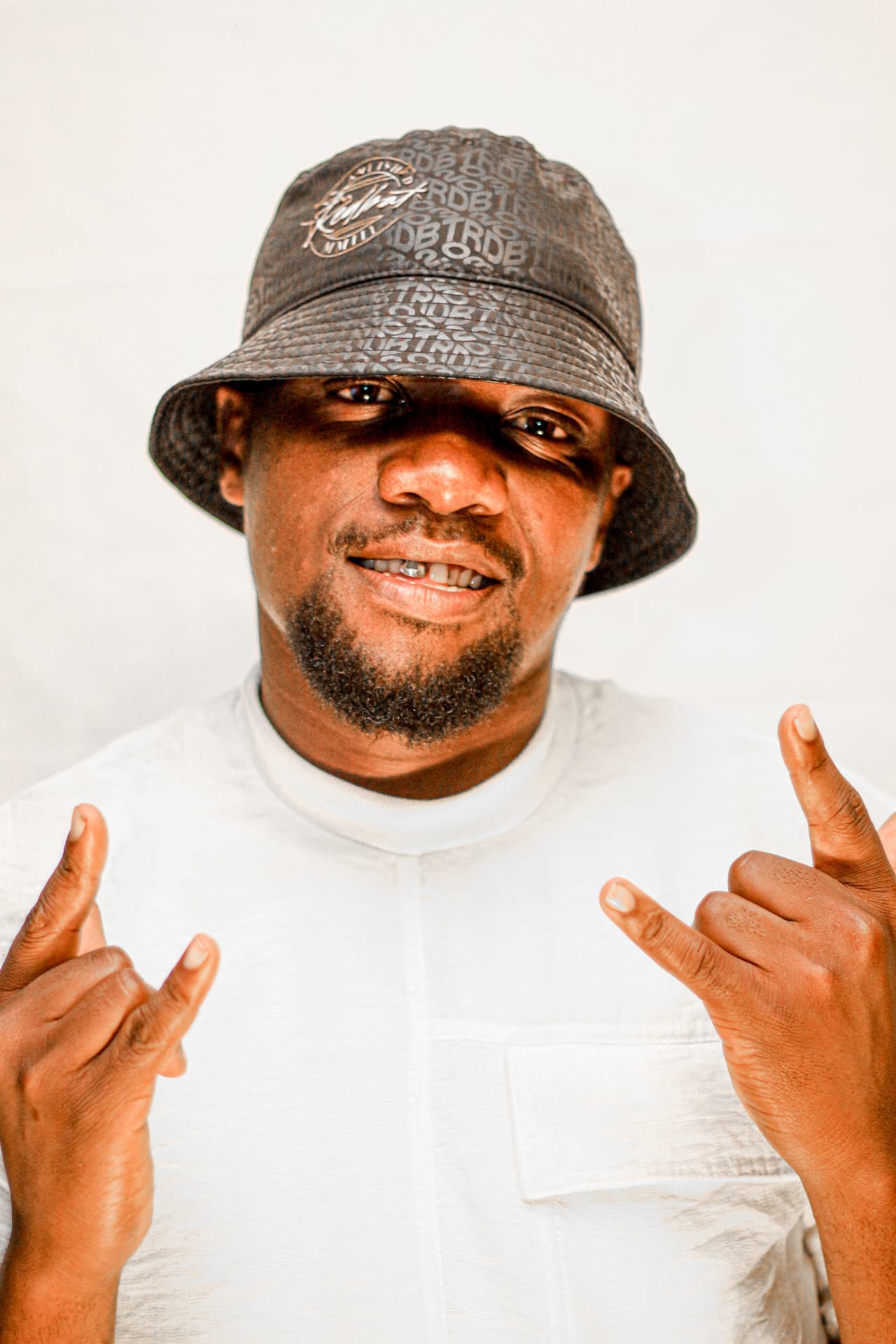Studio portrait of a smiling man in a bucket hat throwing hand signs