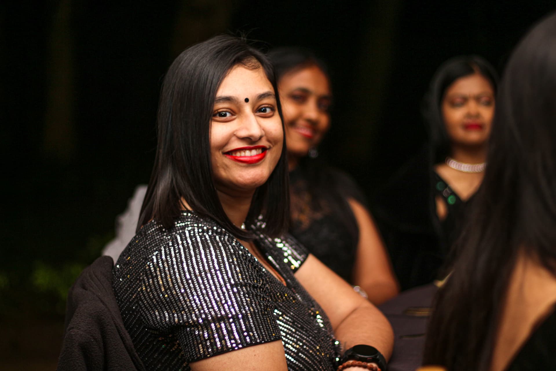 Guests smiling in evening wear under warm light at a 50th birthday celebration