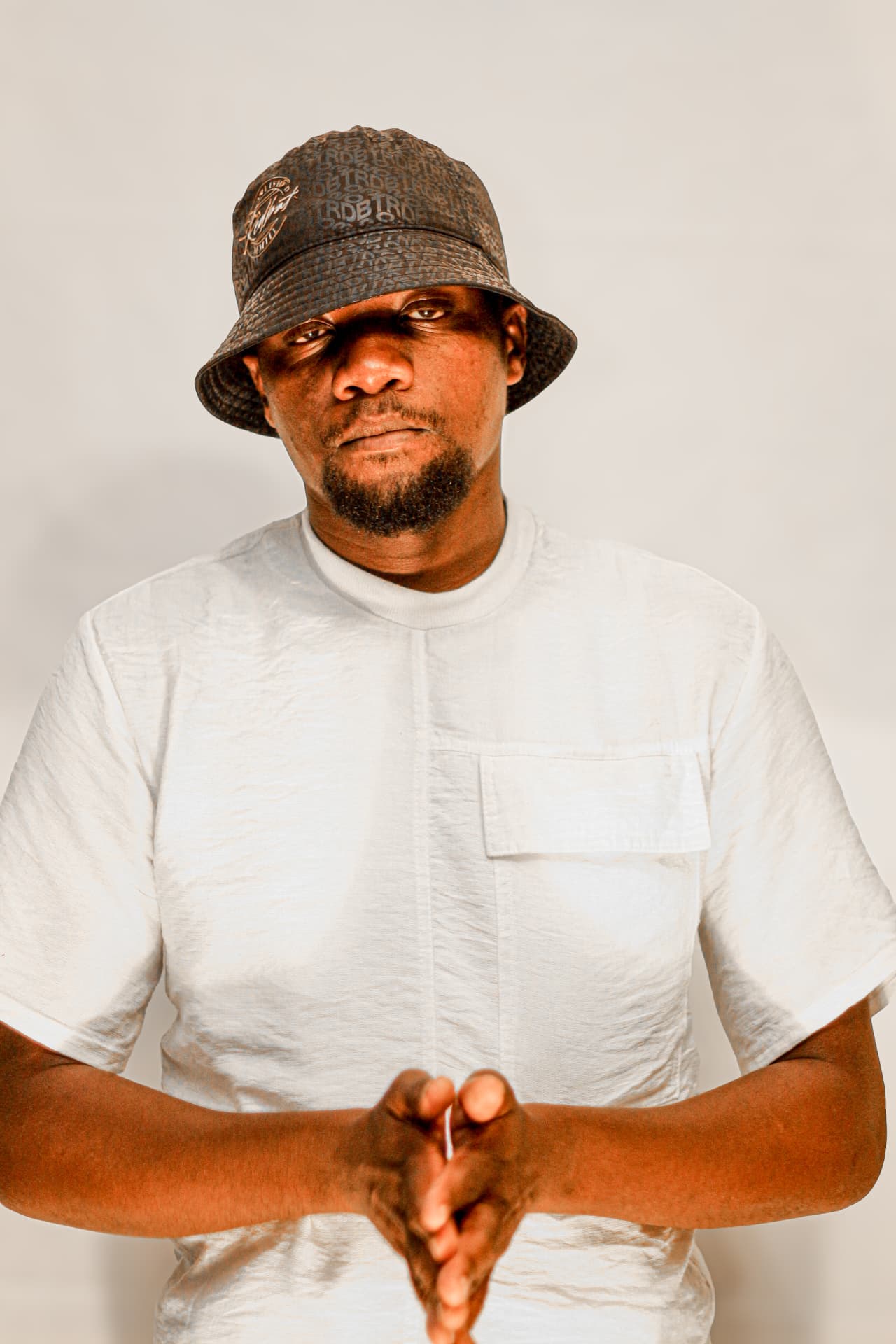 Studio portrait of a man in a white linen shirt and patterned bucket hat