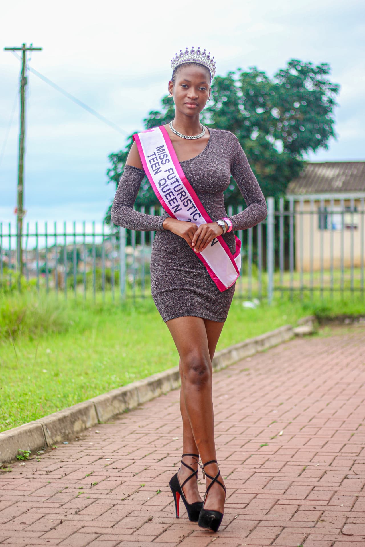 Pageant titleholder photographed walking outdoors with crown and sash