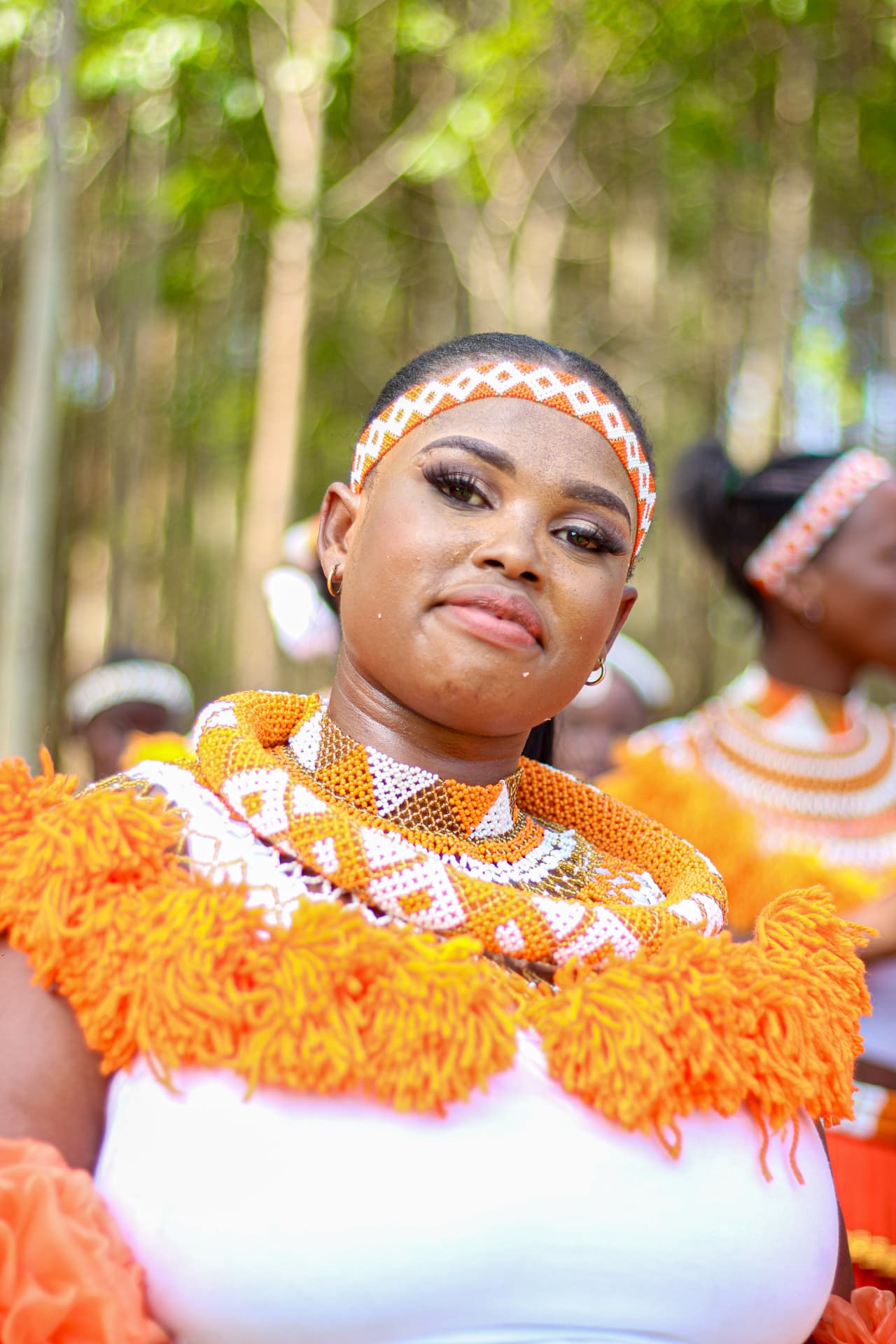 Portrait of a maiden in orange and white Zulu beadwork among the trees