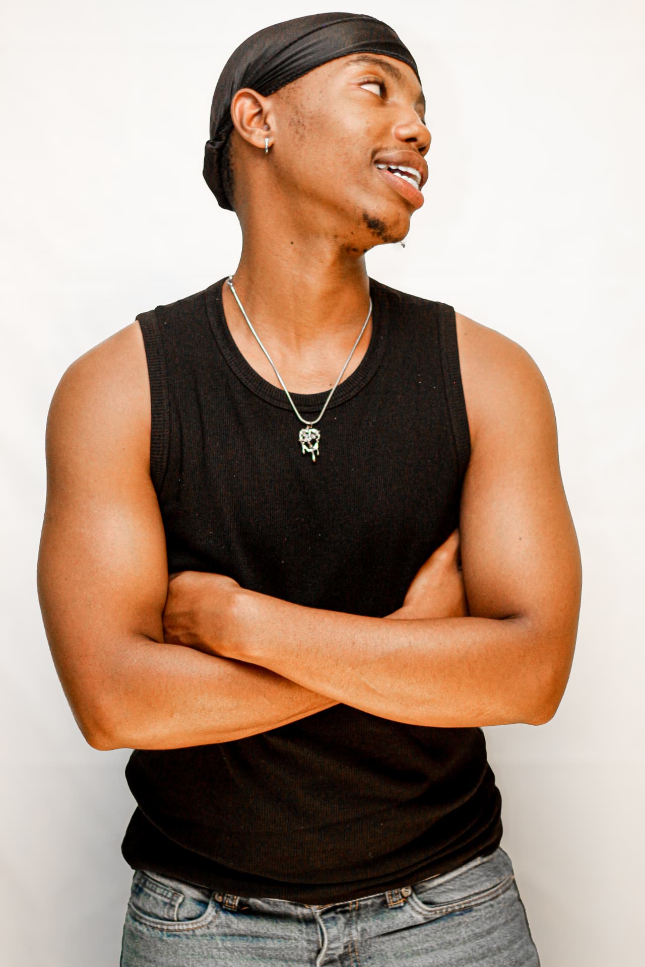 Studio portrait of a young man in a black vest and durag against a bright backdrop