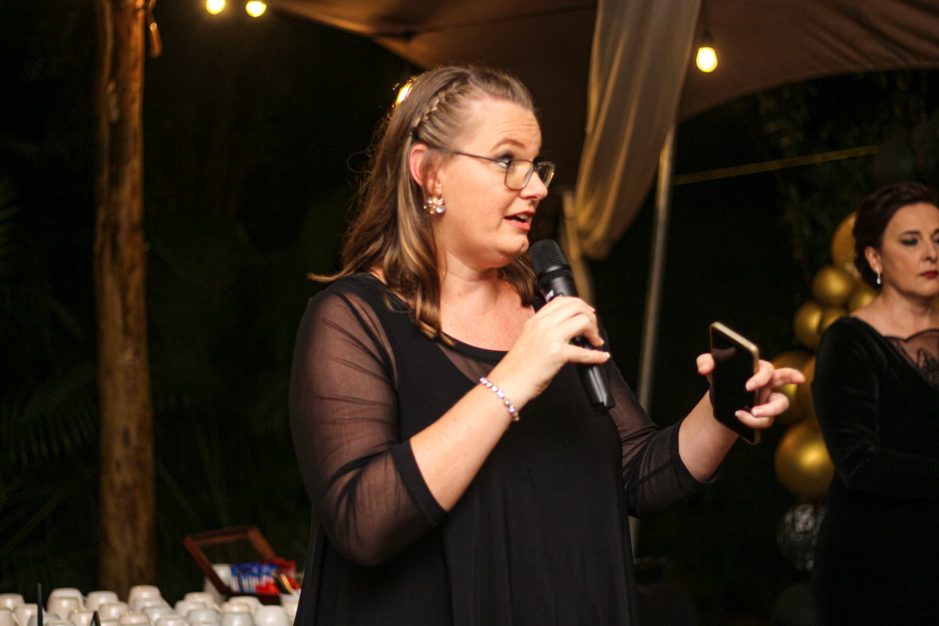 Guest delivering a speech with a microphone at an evening 50th birthday celebration